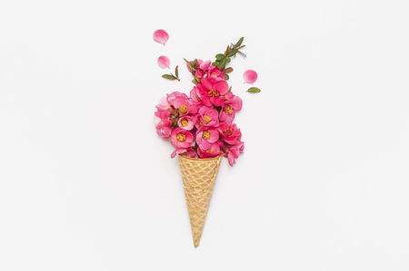 Waffle cone with bouquet of pink spring flowers on light background. Creative spring minimal concept. Flat lay top view copy space. Spring or summer mood concept.の写真素材