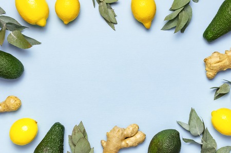 Frame of ripe fresh avocado, citrus lemons, ginger root, eucalyptus twigs on pastel blue background top view Flat lay copy space. Fruits Healthy food concept, diet, healthy lifestyle. Creative food.の写真素材