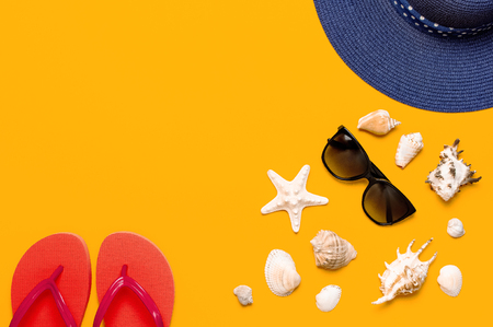 Summer beach sea accessories. Coral flip flops, blue straw hat, sunglasses, shells, starfish on yellow background top view flat lay copy space. Summer background. Holiday vacation travel conceptの写真素材