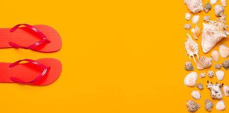 Summer beach sea accessories. Coral flip flops, shells, starfish on yellow background top view flat lay copy space. Summer background. Holiday vacation travel conceptの写真素材