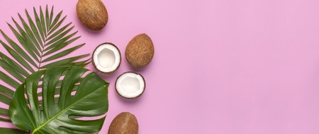 Tropical leaves and fresh coconut on pink background. Flat lay, top view, copy space. Summer background, nature. Healthy cooking. Creative healthy food concept, half of coconut.の写真素材