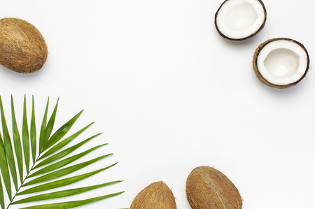 Frame of tropical leaves and fresh coconut on light gray background. Flat lay, top view, copy space. Summer background, nature. Healthy cooking. Creative healthy food concept, half of coconut.の写真素材