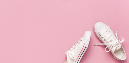 White female fashion sneakers on pink background. Flat lay, top view, copy space. Women's shoes. Stylish white sneakers. Fashion blog or magazine concept. Minimalistic shoe background, sport shoes.の写真素材