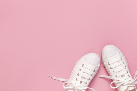 White female fashion sneakers on pink background. Flat lay, top view, copy space. Women's shoes. Stylish white sneakers. Fashion blog or magazine concept. Minimalistic shoe background, sport shoes.の写真素材