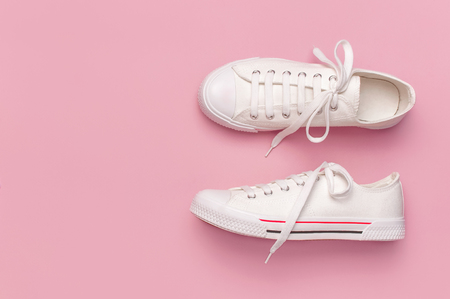 White female fashion sneakers on pink background. Flat lay, top view, copy space. Women's shoes. Stylish white sneakers. Fashion blog or magazine concept. Minimalistic shoe background, sport shoes.の写真素材