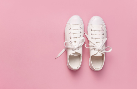 White female fashion sneakers on pink background. Flat lay, top view, copy space. Women's shoes. Stylish white sneakers. Fashion blog or magazine concept. Minimalistic shoe background, sport shoes.の写真素材