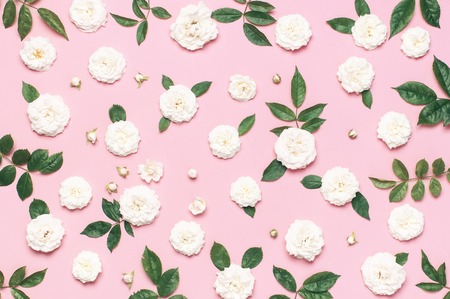 Flowers composition. White fresh roses and green leaves on gentle pink background. Flat lay, top view, copy space. Flower card, greeting, holiday mockup. Valentine's Day background, womens day.の写真素材