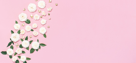 Flowers composition. White fresh roses and green leaves on gentle pink background. Flat lay, top view, copy space. Flower card, greeting, holiday mockup. Valentine's Day background, womens day.の写真素材