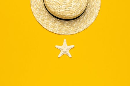 Women s summer straw hat, starfish on yellow background top view flat lay copy space. Summer travel vacation concept, single item. Female accessory, summer background.の写真素材