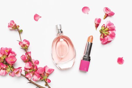 Bottle of women's perfume and lipstick with pink spring flowers on light gray background top view flat lay copy space. Perfumery, cosmetics, female accessories, fragrance collection. Perfume Bottle.の写真素材