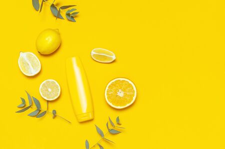 Yellow Cosmetic bottle containers, citrus lemon, orange, eucalyptus on yellow background top view flat lay copy space. Blank label for branding mock-up Natural beauty product sunscreen Summer concept.の写真素材