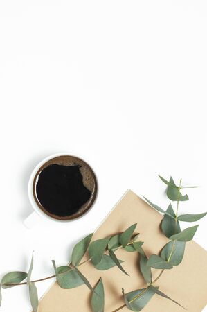 Cup of black coffee, notebook, diary, pens, green sprig of eucalyptus on white background. Flat lay, top view, copy space. Feminine desk workspace, morning breakfast, hot drink, coffee background.の写真素材