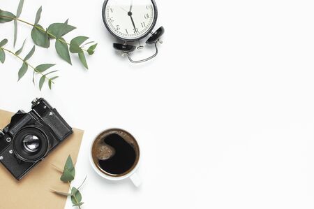 Old retro camera notebook diary cup of coffee eucalyptus leaves on white background. Flat lay top view copy space. Stylish minimal composition artwork mockup Feminine desk workspace.の写真素材