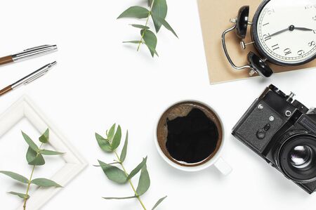Old retro camera notebook diary cup of coffee eucalyptus leaves on white background. Flat lay top view copy space. Stylish minimal composition artwork mockup Feminine desk workspace.の写真素材