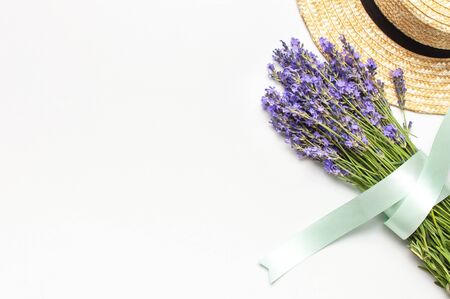 Summer fashion composition. Fresh flowers of purple lavender, women's summer straw hat on light gray background. Flat lay top view copy space. Lavender floral background flower card. Female accessory.の写真素材