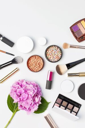 Set of decorative cosmetics mascara powder lipstick eyeshadow blush makeup brush pink hydrangea flowers on light background top view Flat lay copy space. Beauty blogger concept. Fashion background.の写真素材