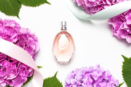 Perfume bottle, pink hydrangea flowers, holiday ribbons on light background top view Flat lay copy space. Perfumery, cosmetics, female accessories, fragrance collection. Delicate Perfume Bottle.の写真素材