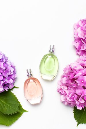 Perfume bottles and pink hydrangea flowers on light gray background top view Flat lay copy space. Perfumery, cosmetics, female accessories, fragrance collection. Delicate Perfume Bottle.の写真素材