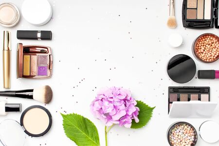 Set of decorative cosmetics mascara powder lipstick eyeshadow blush makeup brush pink hydrangea flowers star confetti on light background top view Flat lay. Beauty blogger concept. Fashion background.の写真素材