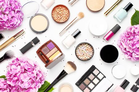 Set of decorative cosmetics mascara powder lipstick eyeshadow blush makeup brush pink hydrangea flowers star confetti on light background top view Flat lay. Beauty blogger concept. Fashion background.の写真素材