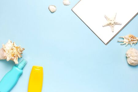 Summer concept, marine background. Seashells, starfish, white blank sheet, sunscreen body spray on blue background. Top view, flat lay, copy space. Sea summer vacation Mockup. Travel, marine souvenirの写真素材