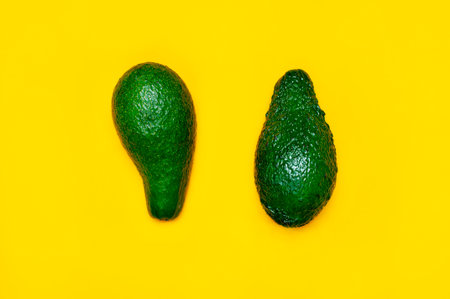 Ripe sliced avocado on bright yellow background top view. Creative food composition Flat lay. Pop...