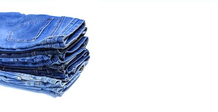 Stack of various blue jeans on white background. Beauty and fashion, clothing concept. Detail of nice blue jeans. Jeans texture or denim background. Collection of jeans.の写真素材