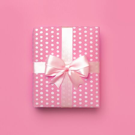 Gift or present box with beautiful festive ribbon on pink background top view. Flat lay composition for celebration, holiday, birthday, Valentines Day, March 8, mother day, wedding. Congratulation.の写真素材