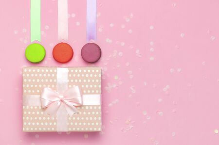 Gift or present box beautiful festive ribbon cake macaron or macaroon confetti on pink background top view. Flat lay composition for celebration holiday birthday, Valentines Day, March 8, mother day.の写真素材
