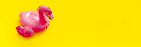 Creative summer beach concept. Inflatable pink mini flamingo on yellow background, pool float party. Flat lay, copy space. Flamingo Trend Inflatable Toy. Summer background. Layout for design.の写真素材
