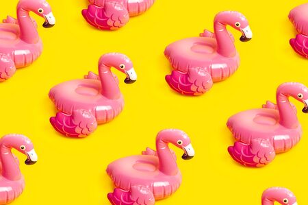 Creative summer beach concept. Pattern from Inflatable pink mini flamingo on yellow background, pool float party. Flat lay, copy space. Flamingo Trend Inflatable Toy. Summer background.の写真素材