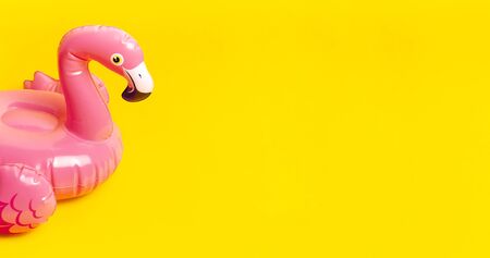 Creative summer beach concept. Inflatable pink mini flamingo on yellow background, pool float party. Flat lay, copy space. Flamingo Trend Inflatable Toy. Summer background. Layout for design.の写真素材
