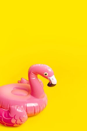 Creative summer beach concept. Inflatable pink mini flamingo on yellow background, pool float party. Flat lay, copy space. Flamingo Trend Inflatable Toy. Summer background. Layout for design.の写真素材