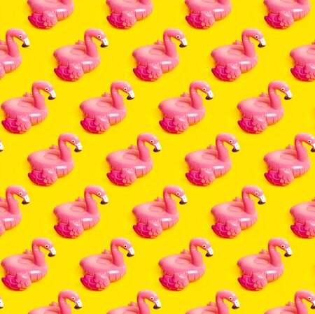 Creative summer beach concept. Seamless pattern from Inflatable pink mini flamingo on yellow background, pool float party. Flat lay, copy space. Flamingo Trend Inflatable Toy. Summer background.の写真素材