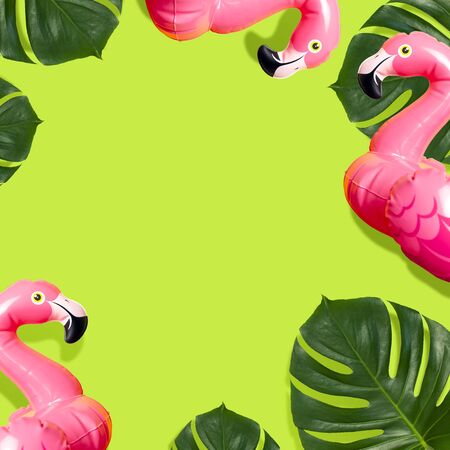 Creative summer beach concept. Inflatable pink mini flamingo and tropical leaf monstera on green background, pool float party. Flat lay copy space. Flamingo Trend Inflatable Toy. Summer background.の写真素材