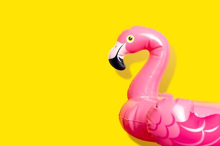 Creative summer beach concept. Inflatable pink mini flamingo on yellow background, pool float party. Flat lay, copy space. Flamingo Trend Inflatable Toy. Summer background. Layout for design.の写真素材
