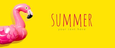 Creative summer beach concept. Inflatable pink mini flamingo on yellow background, pool float party. Flat lay, copy space. Flamingo Trend Inflatable Toy. Summer background. Layout for design.の写真素材