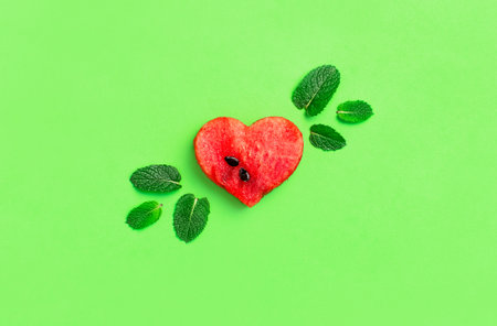 Creative summer food concept. Juicy slices of ripe red watermelon in the shape of a heart and mint...
