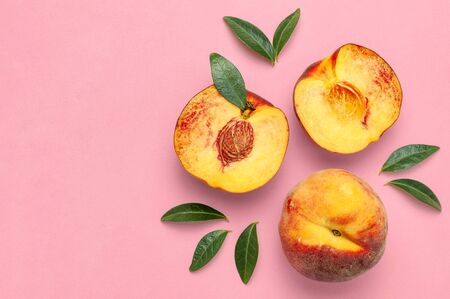 Flat lay composition with peaches. Ripe juicy peaches with green leaves on pink background. Flat lay, top view, copy space.の写真素材