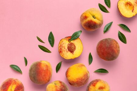 Flat lay composition with peaches. Ripe juicy peaches with green leaves on pink background. Flat lay, top view, copy space.の写真素材