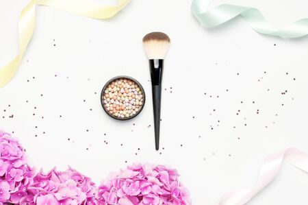 Set of decorative cosmetics makeup brushes, blush face balls, pink hydrangea flowers, star confetti, holiday ribbons on light backgroundの写真素材