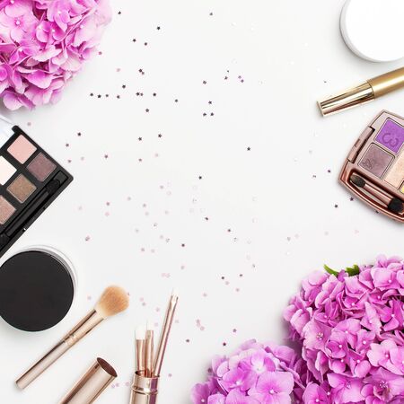 Set of decorative cosmetics mascara powder lipstick eyeshadow blush makeup brush pink hydrangea flowers star confetti on light backgroundの写真素材