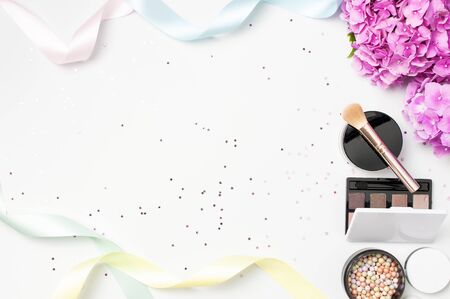Set of decorative cosmetics mascara powder lipstick eyeshadow blush makeup brush pink hydrangea flowers star confetti on light backgroundの写真素材