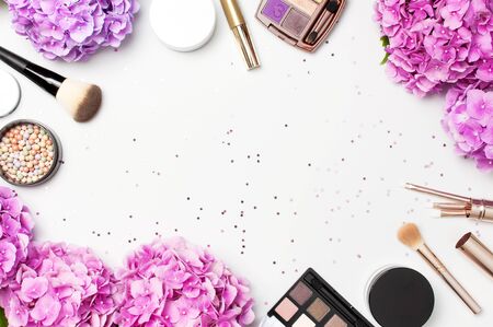 Set of decorative cosmetics mascara powder lipstick eyeshadow blush makeup brush pink hydrangea flowers star confetti on light backgroundの写真素材