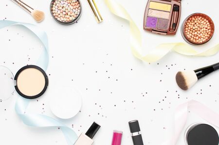 Set of decorative cosmetics mascara powder lipstick eyeshadow blush makeup brush, star confetti holiday ribbons on light backgroundの写真素材