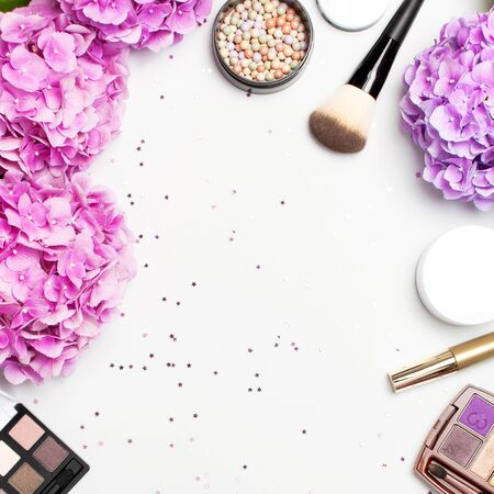 Set of decorative cosmetics mascara powder lipstick eyeshadow blush makeup brush pink hydrangea flowers star confetti on light backgroundの写真素材