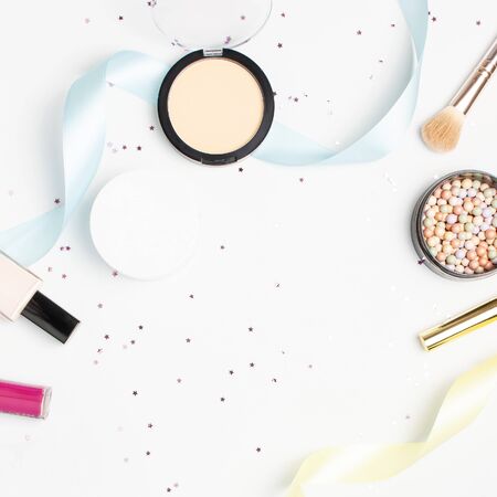 Set of decorative cosmetics mascara powder lipstick eyeshadow blush makeup brush, star confetti holiday ribbons on light backgroundの写真素材