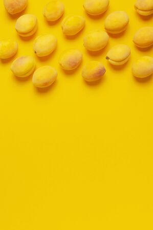 Ripe fresh apricots fruits on yellow background. Flat lay, top view, copy space.の写真素材