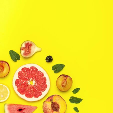 Tropical Summer Fruit Concept. Creative layout made of fresh ripe watermelon, peach, plum, fig, lemon, grapefruit and mint leaves on yellow background. Flat lay, top view, copy space. Food background.の写真素材