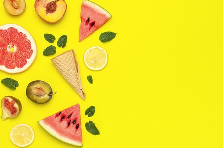 Tropical Summer Fruit Concept. Creative layout made of fresh ripe watermelon, peach, plum, fig, lemon, grapefruit, waffle ice cream cup, mint leaves on yellow background. Flat lay top view copy space.の写真素材